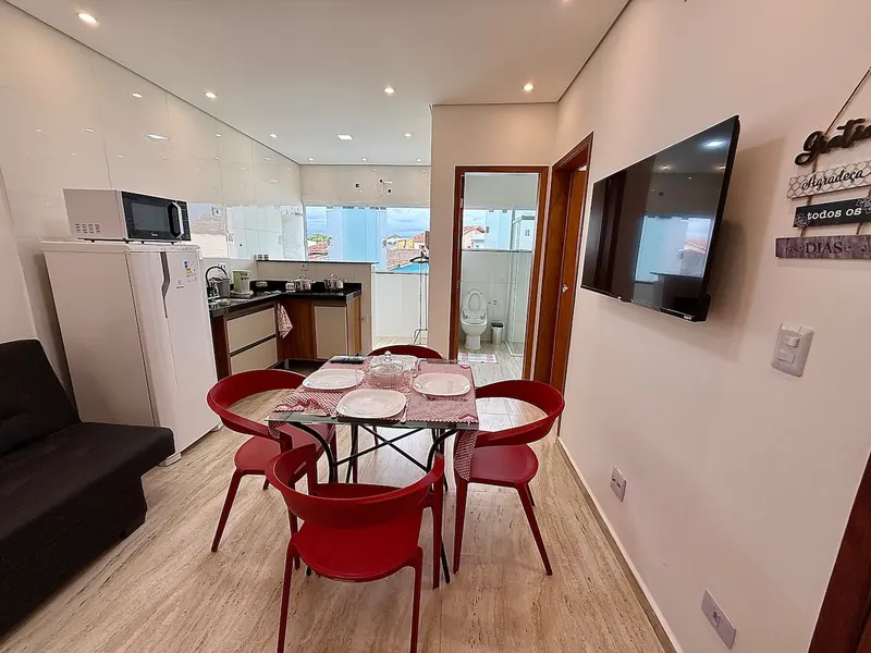 Sala e cozinha do apartamento 01, com mesa posta e cadeiras vermelhas