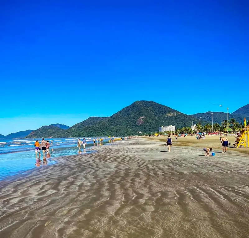 Mar, areia e morros na orla de Peruíbe, em um dia de sol